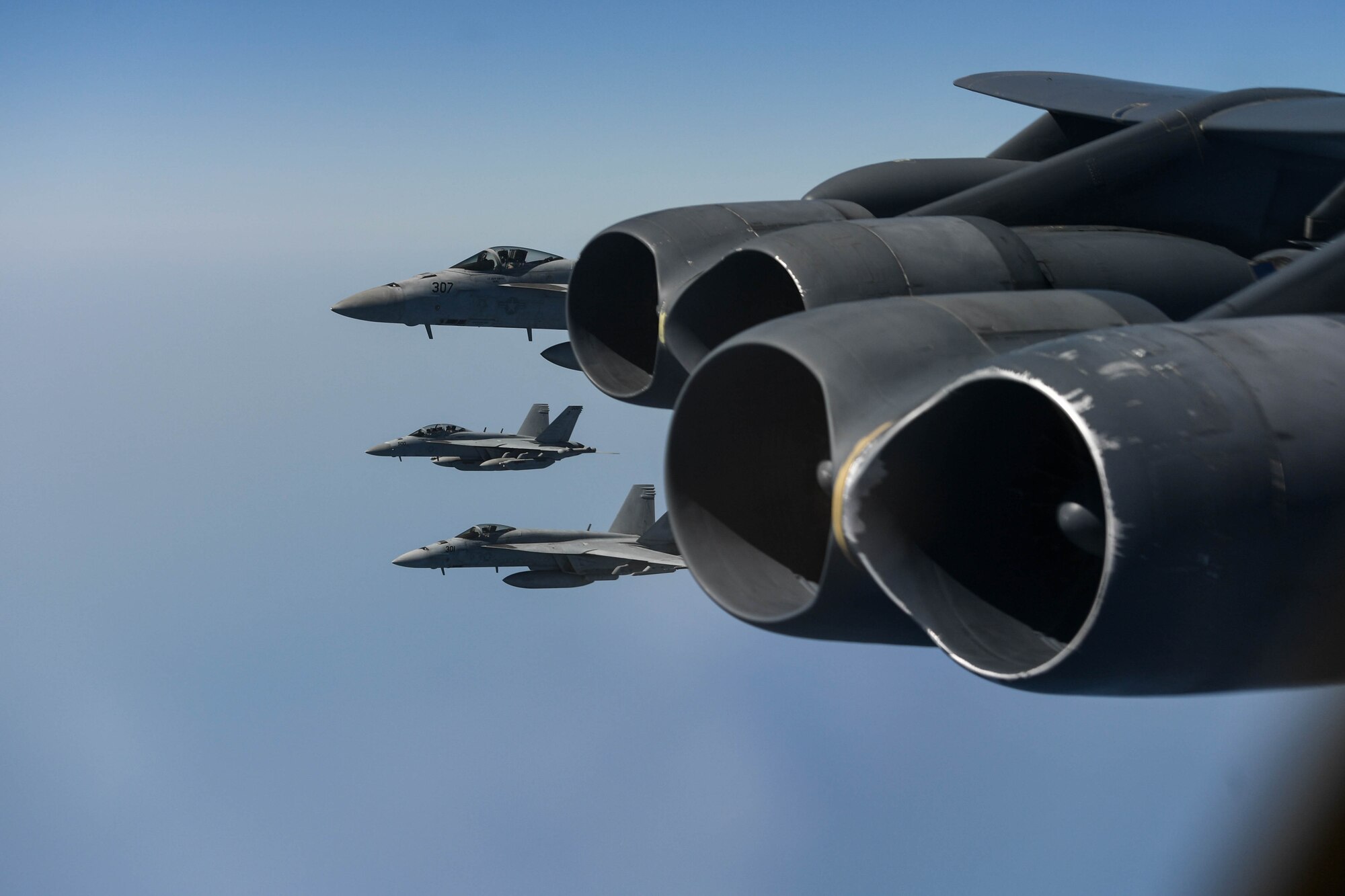 A photo of F-18 Hornets flying next to a B-52 Stratofortress.