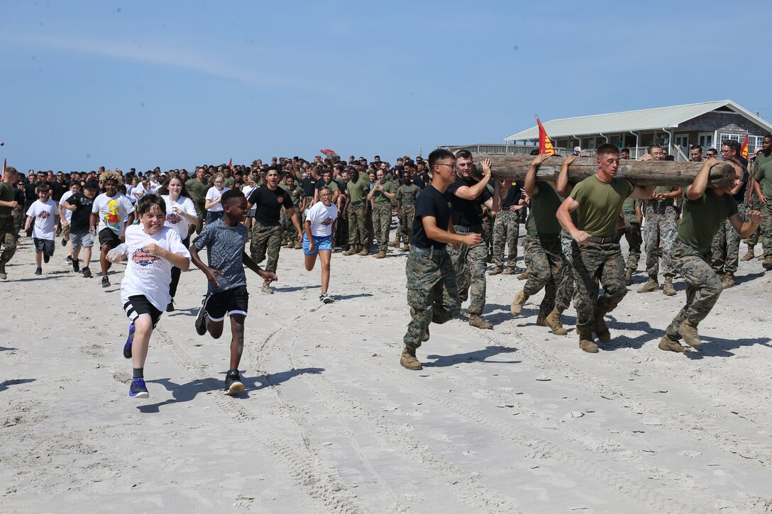 Students from Parkwood Elementary School run alongside Marines during a log run competition at a Commander’s Cup event with 2nd Transportation Battalion, Combat Logistics Regiment 2, 2nd Marine Logistics Group at Onslow Beach, May 24, 2019. The unit adopted Parkwood Elementary in January 2019 School and are volunteering their time with students weekly. (U.S. Marine Corps photo by Cpl. Ashley Lawson)