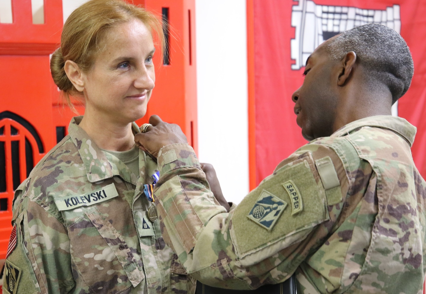 Col. Jason E. Kelly pins on the third of three medals awarded to Emilija Kolevski as she ends her deployment in support of the Afghanistan USACE District.