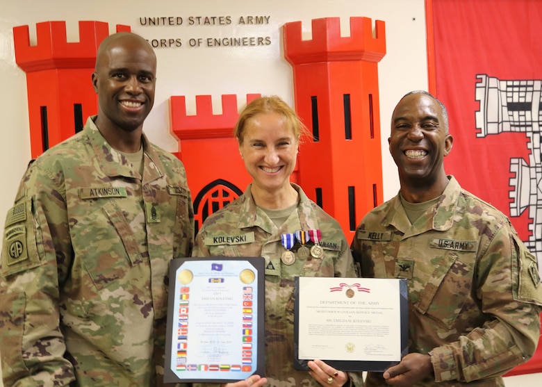 Emilija Kolevski proudly displays her NATO, Global War on Terrorism, and Meritorious Civilian Service Medals as Command Sergeant Major Nate Atkinson and Commanding Officer, Col. Jason E. Kelly, Afghanistan District support the redeployment of Kolevski to her home station.