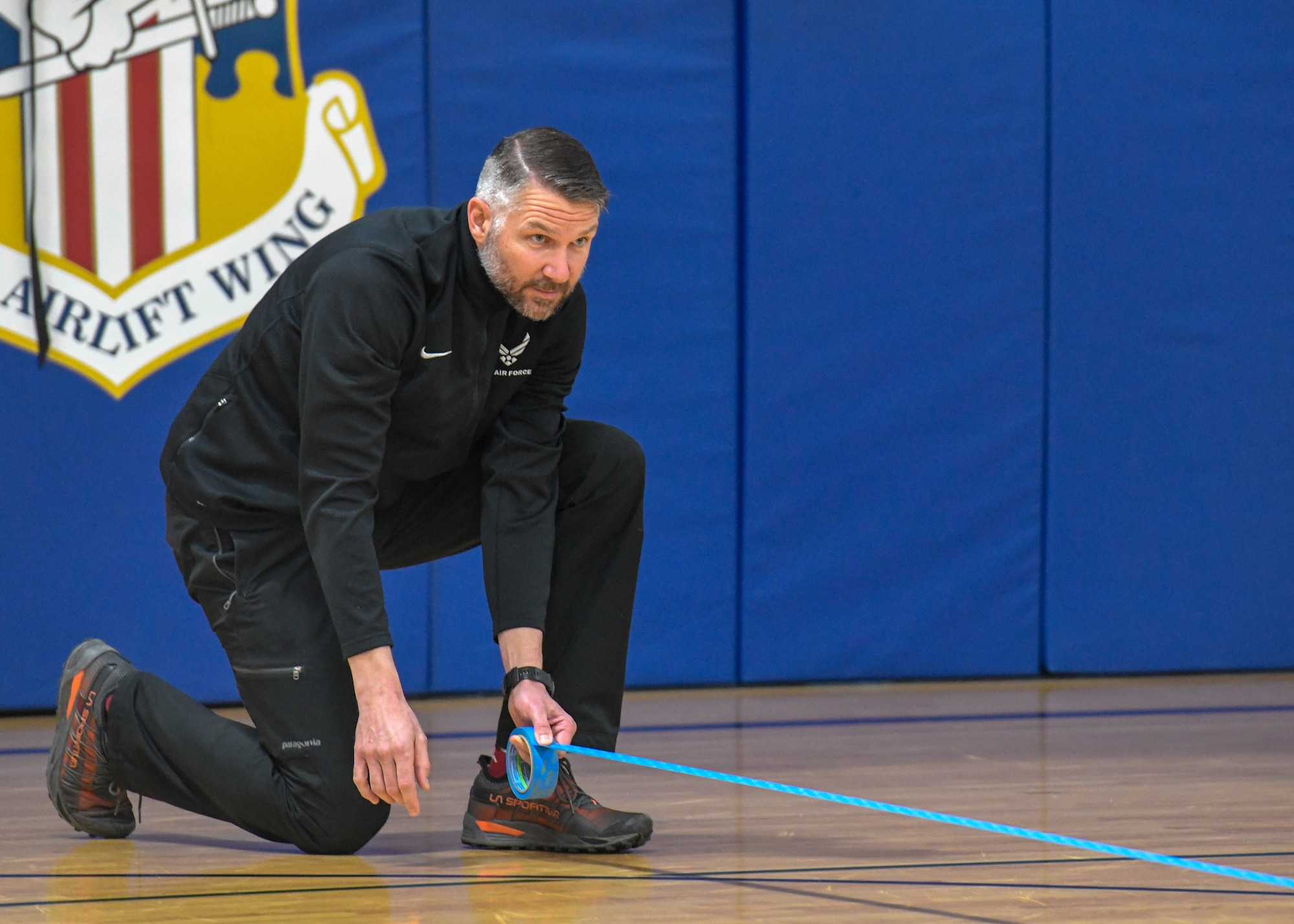Matthew Gruse, exercise physiologist for the 910th Airlift Wing, puts tape on the gym floor marking the start line for a beep test here, April 18, 2019.