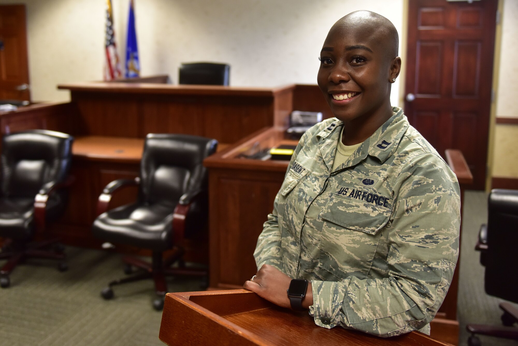 A woman wearing the Airman Battle Uniform stands in front of a judge seat.