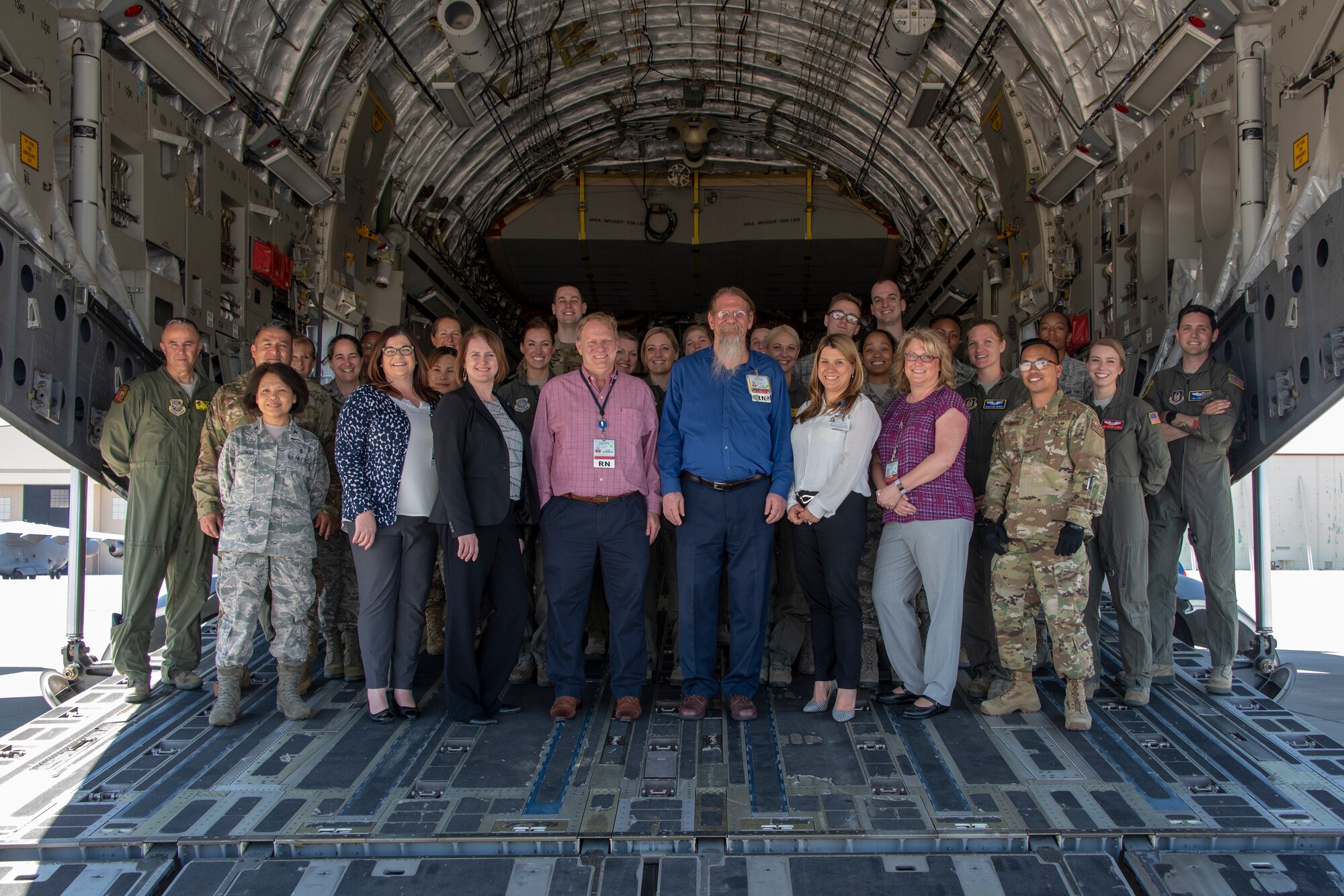 U.S. Air Force and civilian medical professionals pose for a photo on the aft loading ramp of a C-17 Globemaster III aircraft April 17, 2019, at Travis Air Force Base, California. Registered nurses from North Bay Healthcare Medical Center and the University of California Davis Medical Center spent the day touring several departments at David Grant USAF Medical Center and observed a patient transport demons