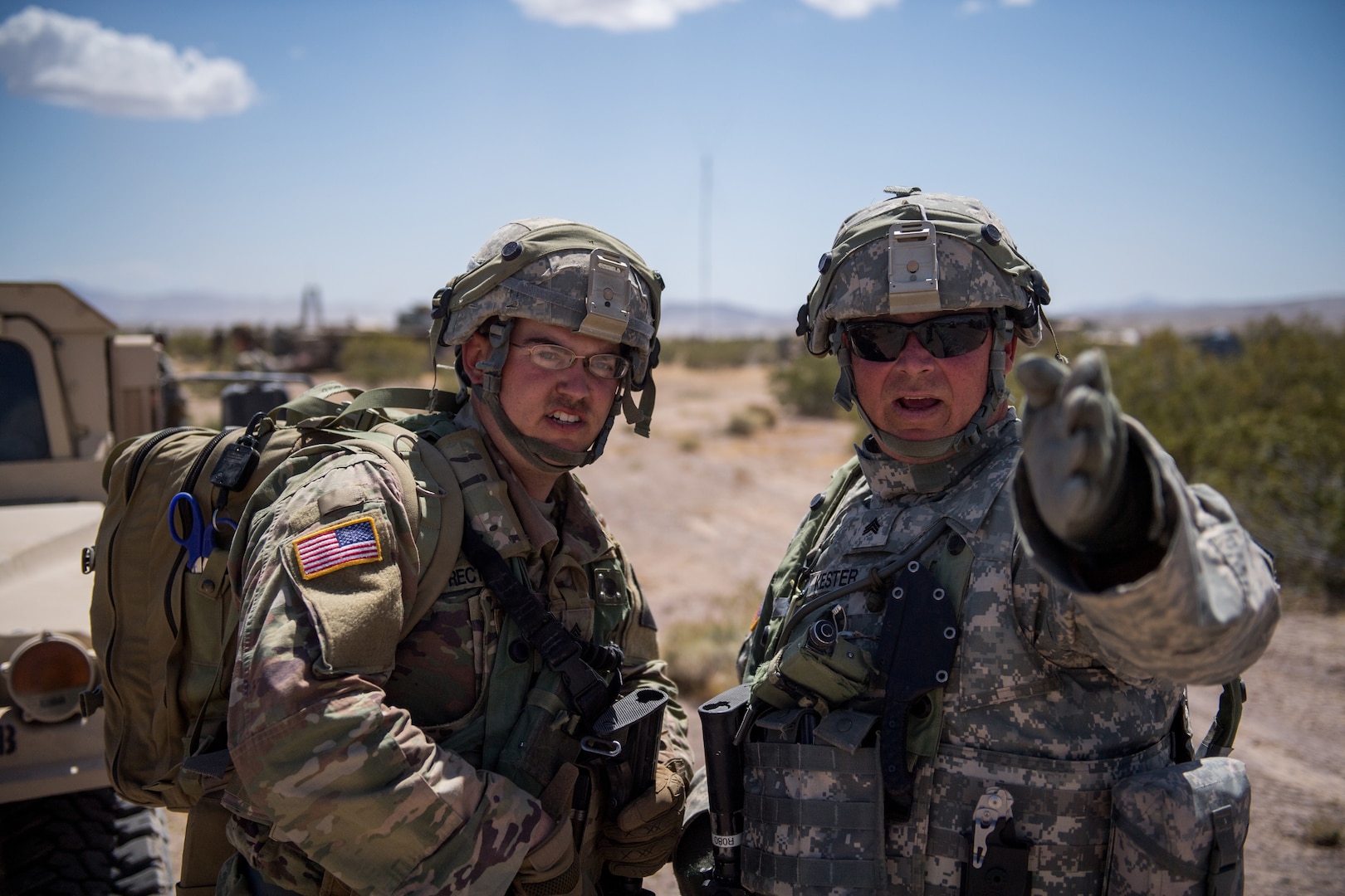 Kansas Army National Guard Sgt. Kenneth Kester and Sgt. Christopher Rectenwald, 242nd Engineer Company, discusses the outer perimeter of the tactical assembly area June 1, 2019, at Fort Irwin, California. Rectenwald is assigned to the 242nd Engineer Company as a 68W combat medic.