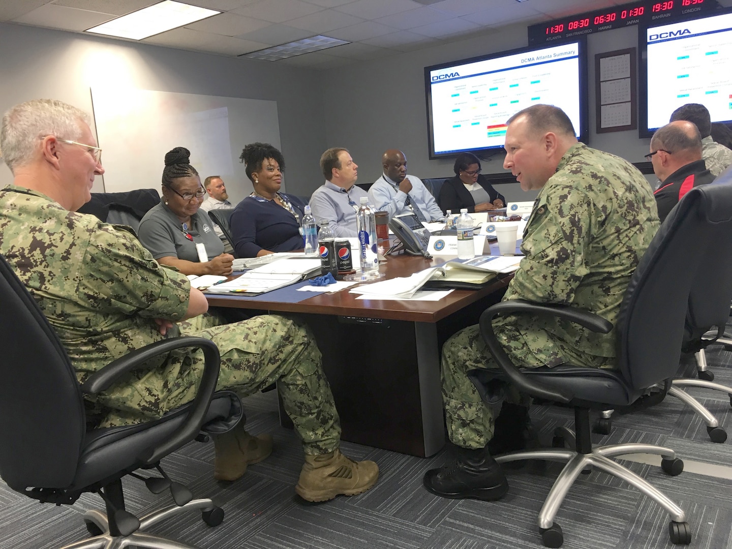 Group of men and women talking to each other while sitting at a table.