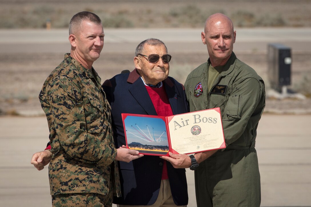 U.S. Marine Corps Col. David A. Suggs (right), commanding officer, Marine Corps Air Station (MCAS) Yuma and U.S. Marine Corps Sgt. Maj. David M. Leikwold (left), sergeant major, MCAS Yuma, present the "Air Boss" award to Mr. Jacques-Andre Istel (center) during the opening ceremony of the 2019 Yuma Twilight Show hosted by (MCAS) Yuma Ariz., March 9, 2019. The airshow is MCAS Yuma's only military airshow of the year and provides the community an opportunity to see thrilling aerial and ground performers for free while interacting with Marines and Sailors. (U.S. Marine Corps photo by Sgt. Allison Lotz)