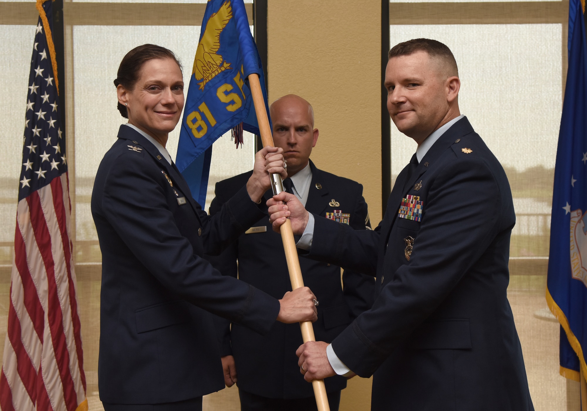 U.S. Air Force Col. Marcia Quigley, 81st Mission Support Group commander, passes the 81st Security Forces Squadron guidon to Maj. Matthew Lowe, incoming 81st SFS commander, during the 81st SFS change of command ceremony inside the Bay Breeze Event Center at Keesler Air Force Base, Mississippi, May 31, 2019. The passing of the guidon is a ceremonial symbol of exchanging command from one commander to another. (U.S. Air Force photo by Kemberly Groue)