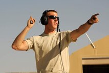 An Airman signals an aircraft.