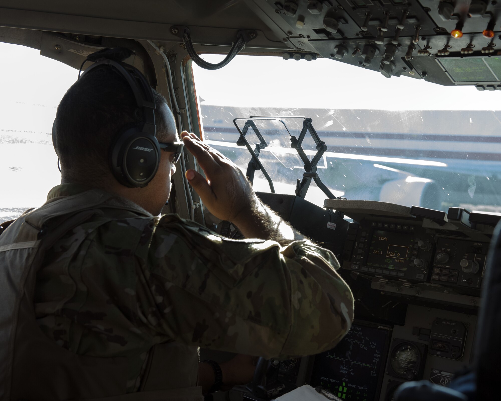 U.S. Air Force Maj. Roger Gates, 21st Airlift Squadron pilot, renders a salute from a C-17 Globemaster III to a passing aircraft on the flight line at Bagram Airfield, Afghanistan, May 26, 2019. The C-17 is capable of rapid strategic delivery of troops and cargo anywhere in the world. (U.S. Air Force photo by Tech. Sgt. Traci Keller)