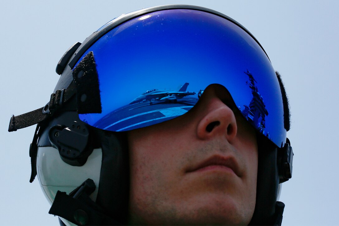 Aircraft are reflected on the blue helmet of a pilot.