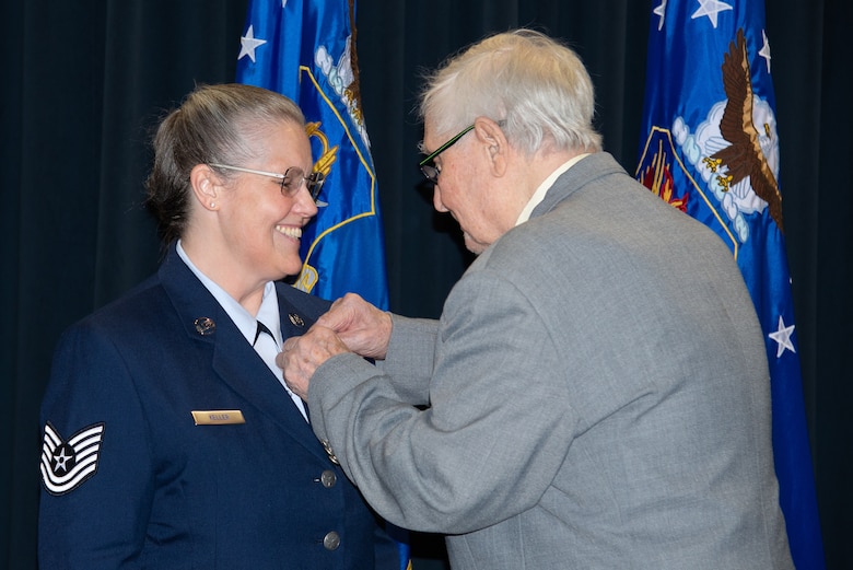 Donald Asmussen places a retirement pin onto Tech. Sgt. Tanya Keller, 302nd Maintenance Group Plans, Scheduling and Documentation production controller, during her retirement ceremony June 2, 2019 at Peterson Air Force Base, Colorado.