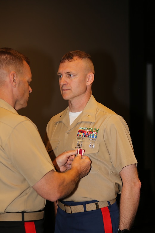Maj. Travis S. Bowser, right, operations officer, Physical Inventory Control Division, G4, MARCORLOGCOM, receives the Meritorious Service Medal from Maj.Gen. Joseph F. Shrader, commanding general, MARCORLOGCOM, during a ceremony held at Base Theatre aboard MARCORLOGBASES Albany, GA., May 30. Bowser served 24 years in the Marine Corps.