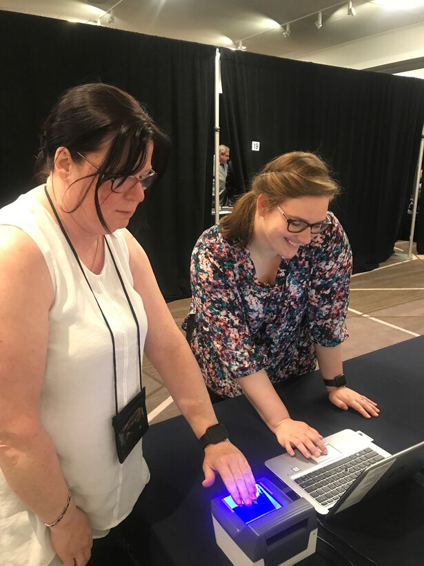 Left to right, Brenda Curry and Julie LeCave, AFLCMC security specialists, test out the fingerprinting equipment at the AFLCMC recruitment and hiring event on May 29 at the Marriott hotel in Dayton, Ohio.  Both Curry and LeCave are on hand at the event to help expedite the e-QIP investigation process for new hires. (U.S. Air Force photo/Stacey Geiger)