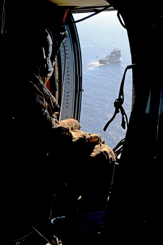 An Army Soldier observes a helicopter preparing to land on a ship.