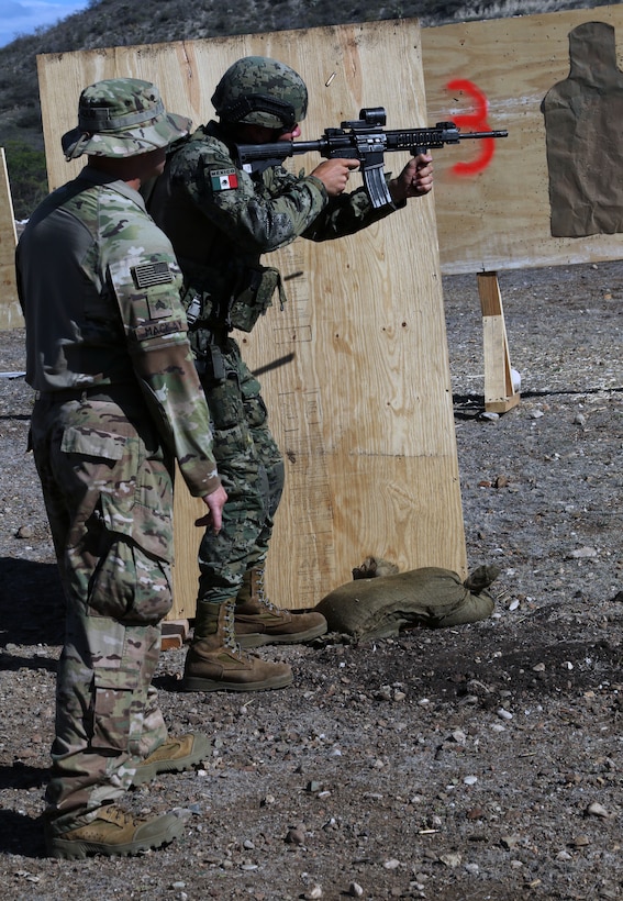 A U.S. Army Soldier coaches a member of the Mexican Marines during weapons training