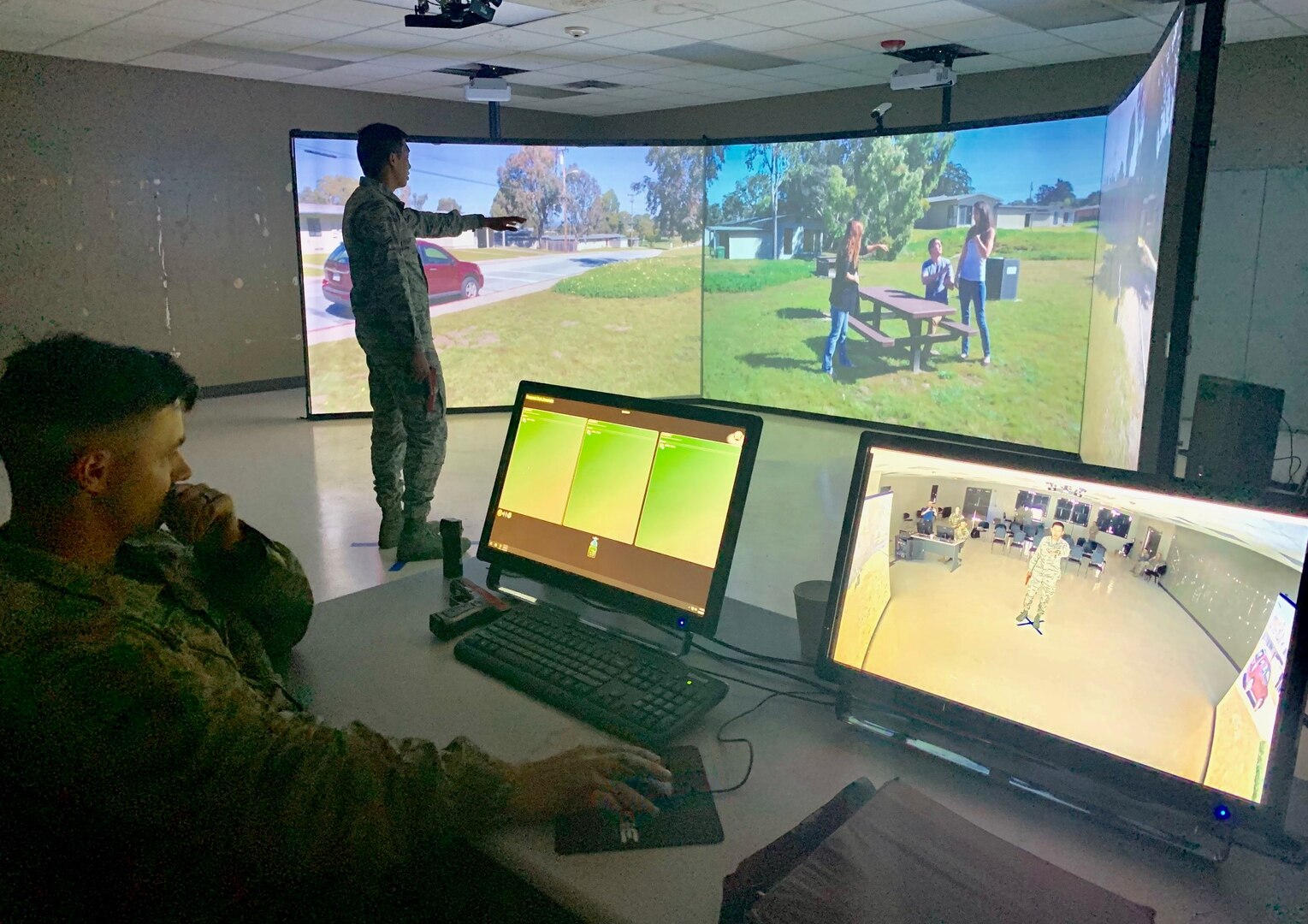 Airman 1st Class Valric Suyom, a recent graduate of the Security Forces apprentice course, participates in a use of force training scenario in the Multiple Interactive Learning Objectives, or MILO, simulator as Staff Sgt. James McKinney, 343rd Training Squadron instructor, guides the training at Joint Base San Antonio-Lackland May 29. The MILO system puts student in various interactive use of force training scenarios, including the potential application of deadly force, through the use of enhanced video screens.