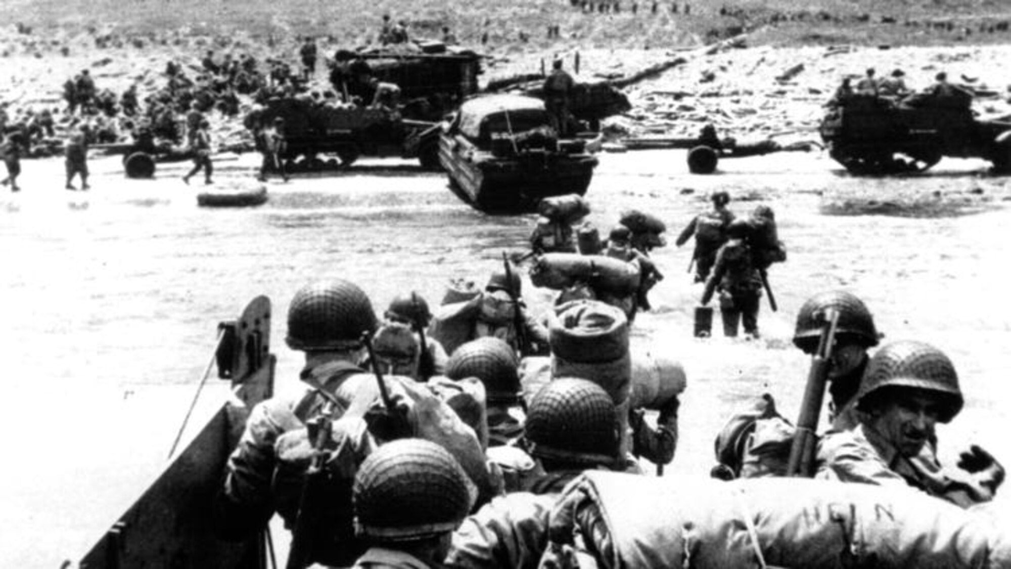 Amphibious trucks and a half-track follow troops ashore during the World War II D-Day invasion of France on a 50-mile front along the Normandy coast by Allied forces on June 6, 1944