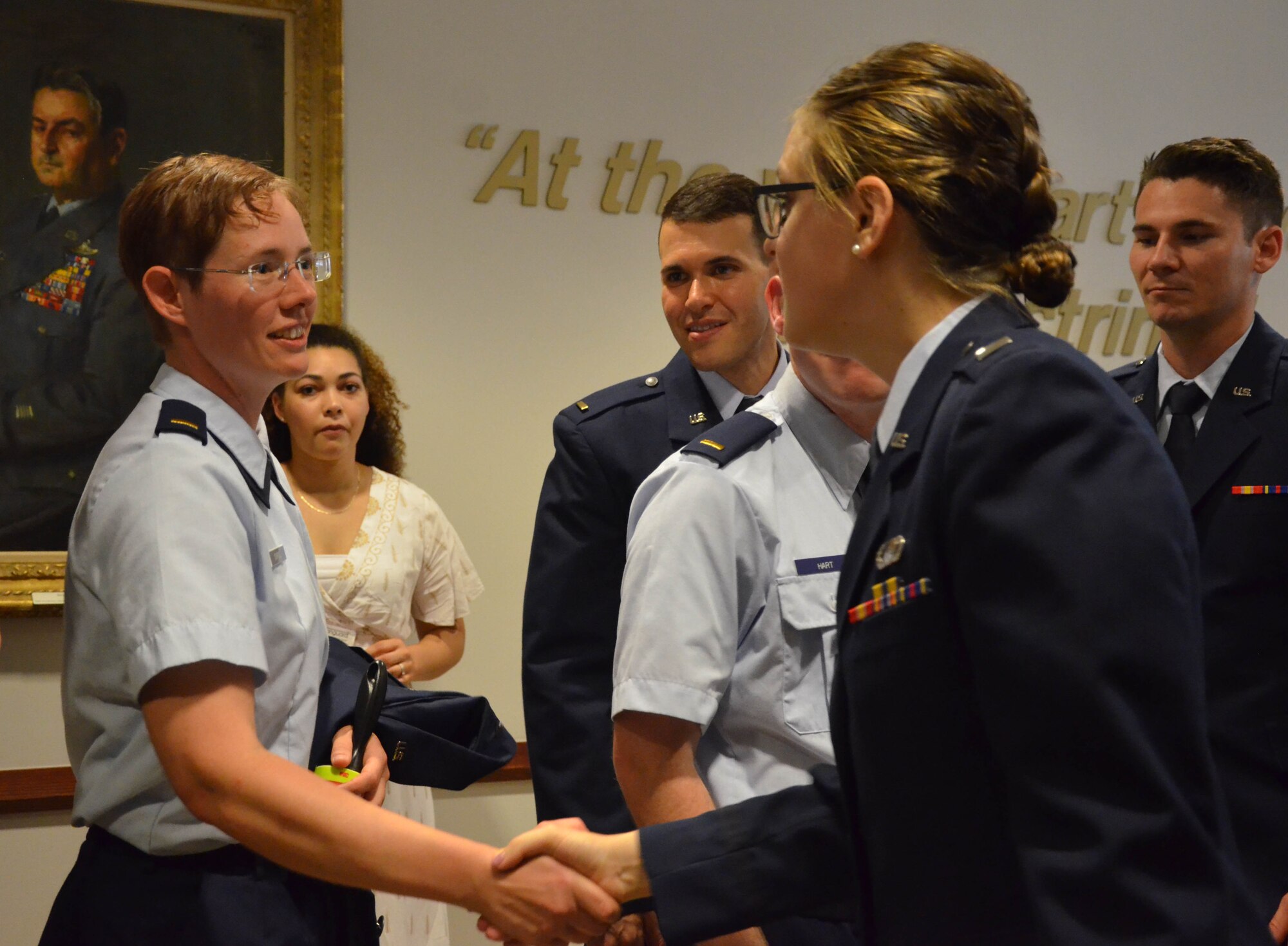 2nd Lt. Cynthia A. Schroll (left) shakes hands with her Officer Training School instructor, 1st Lt. Claire M. Krokker, after Schroll's commissioning ceremony May 30, 2019, as members of her flight look on.  (U.S. Air Force photo by Susan A. Romano)