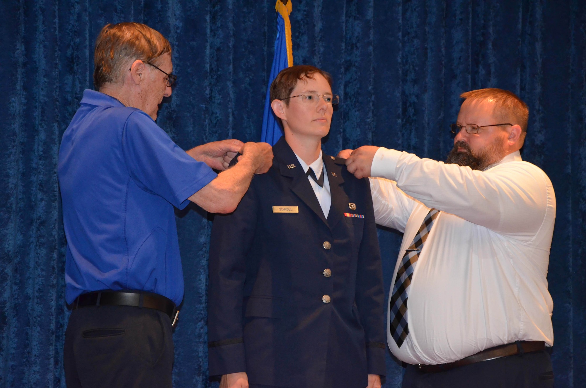2nd Lt. Cynthia A. Schroll (center) stands at attention as her father Stephen (left) and brother Brandon (right) pin on her second lieutenant bars after she took the oath of commissioning at Officer Training School May 30, 2019.  (U.S. Air Force photo by Susan A. Romano)