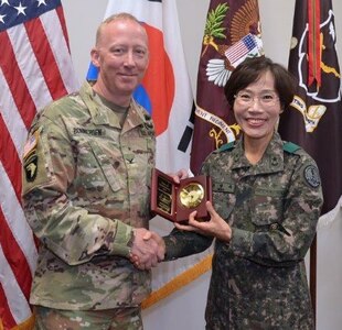 Col. Daniel Bonnichsen, U.S. Army Medical Department Center & School, Health Readiness Center of Excellence chief of staff and Republic of Korea Army Brigadier General Myoung-ok Kwon, superintendent for the Korea Armed Forces Nursing Academy, conduct a gift exchange during a visit to Joint Base San Antonio-Fort Sam Houston May 30.