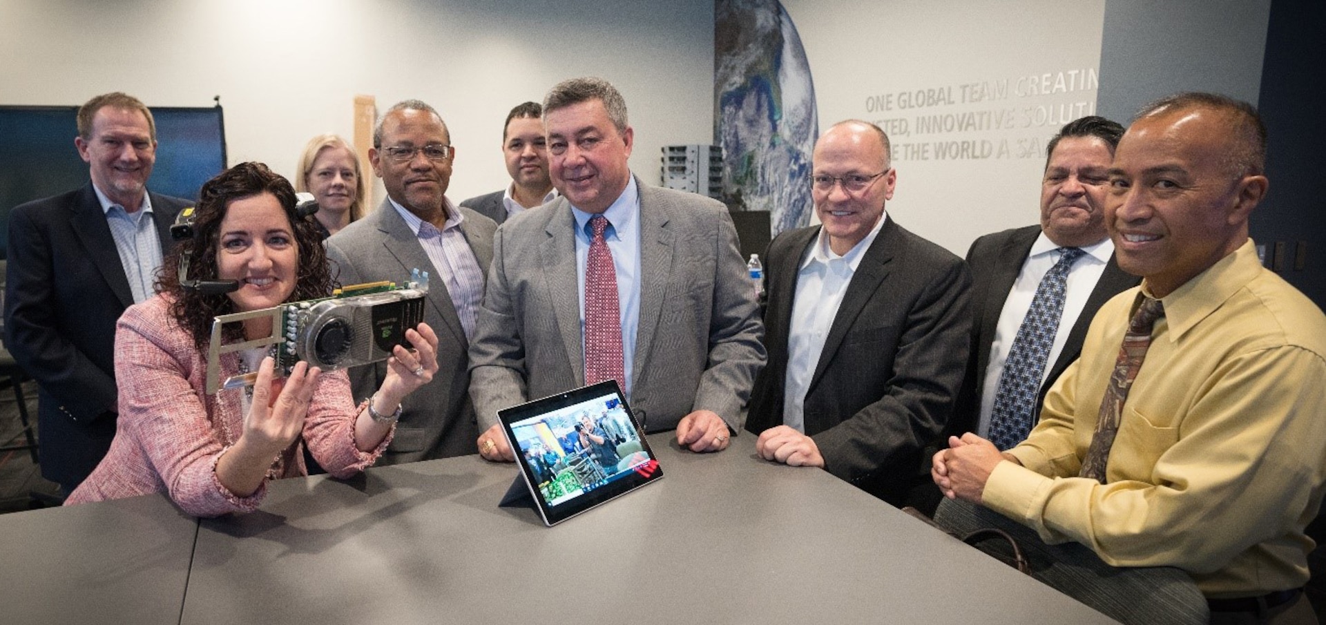 Group photo of smiling men and women standing around a table