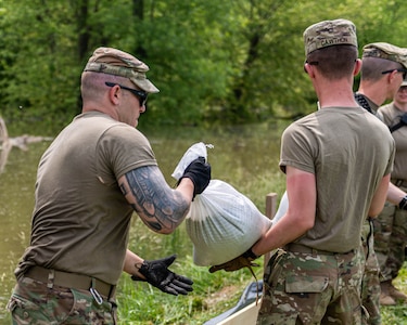 Spc. Jared Jess, of Jacksonville, Illinois, grabs a sandbag from Pvt. 1st Class Killian Cawthon, of Watseka, Illinois, both Soldiers serve with Bravo Battery, 2nd Battalion, 123rd Field Artillery Regiment, based in Springfield, Illinois. Soldiers of Bravo Battery worked along the 12 miles of levee that make up the Heartwell Levee District in Greene County, Illinois.