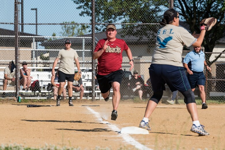 Col. Matthew Jones, 436th Airlift Wing vice commander, runs toward first base during the Chiefs versus Colonels softball game June 3, 2019, at Dover Air Force Base, Del. Chief Master Sgt. Danielle Hirvela, Air Force Mortuary Affairs Operations chief enlisted manager, waits for the ball at first base while Chief Master Sgt. Anthony Green, 436th AW command chief, looks at the play from home plate. (U.S. Air Force photo by Roland Balik)