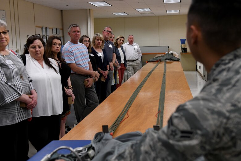 Airman First Class Austyn Foreman, 97th Operations Support Squadron Aircrew Flight Equipment journeyman, shows the honorary commanders the BA-22 Parachute System during the Honorary Commanders Boot Camp, May 31, 2019, at Altus Air Force Base, Okla. After briefing the honorary commanders on the different sections of the OSS, they were shown the Aircrew Flight Equipment shop. (U.S. Air Force Photo by Senior Airman Jackson N. Haddon)