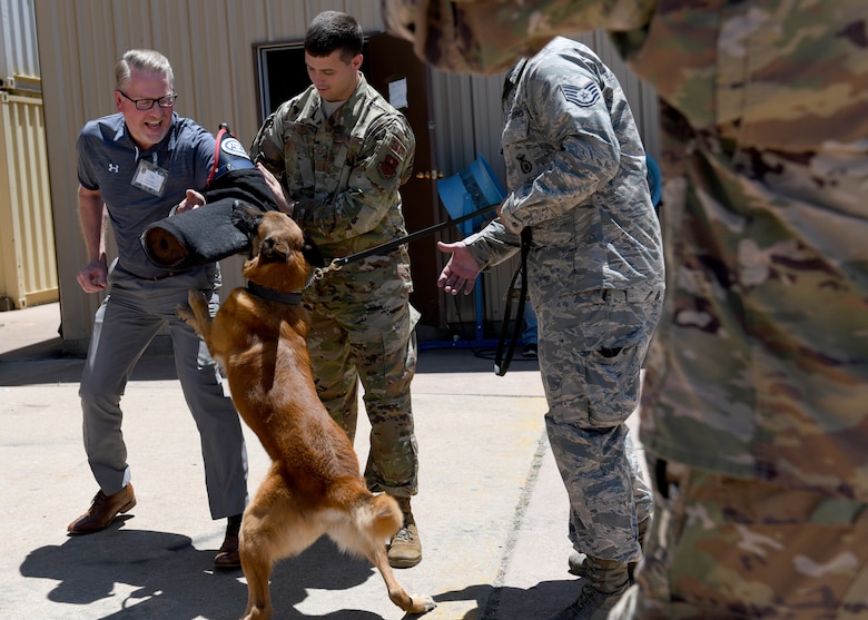 Tech. Sgt. Joseph Teresi, 97th Security Forces NCO in charge of the Military Working Dogs (MWD) Section, helps Roe Worbes, honorary commander for the 97th Mission Support Group, handle a MWD, May 31, 2019, at Altus Air Force Base, Okla. During the Honorary Commanders Boot Camp, the 97th MSG showcased their units, to include the new Security Forces Squadron Warrior Training Center. (U.S. Air Force Photo by Senior Airman Jackson N. Haddon)