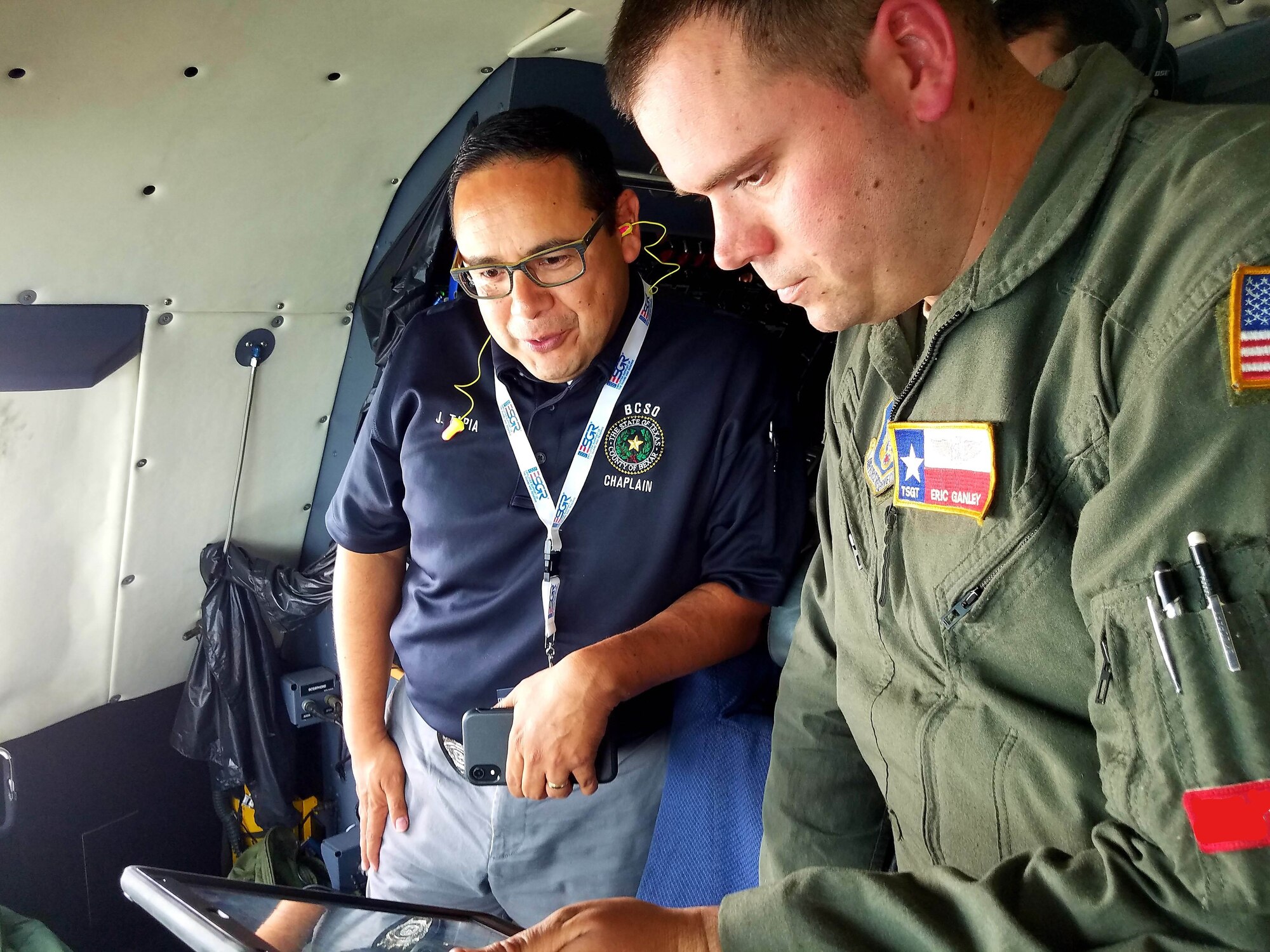 Tech. Sgt. Eric Ganley (right), 68th Airlift Squadron flight engineer, uses an electronic tablet to show Josue Tapia, Bexar County Sheriff’s Office chaplain, their location in-flight on a C-5M Super Galaxy during the 433rd Airlift Wing’s annual Clergy Day flight June 1, 2019 at Joint Base San Antonio-Lackland, Texas.