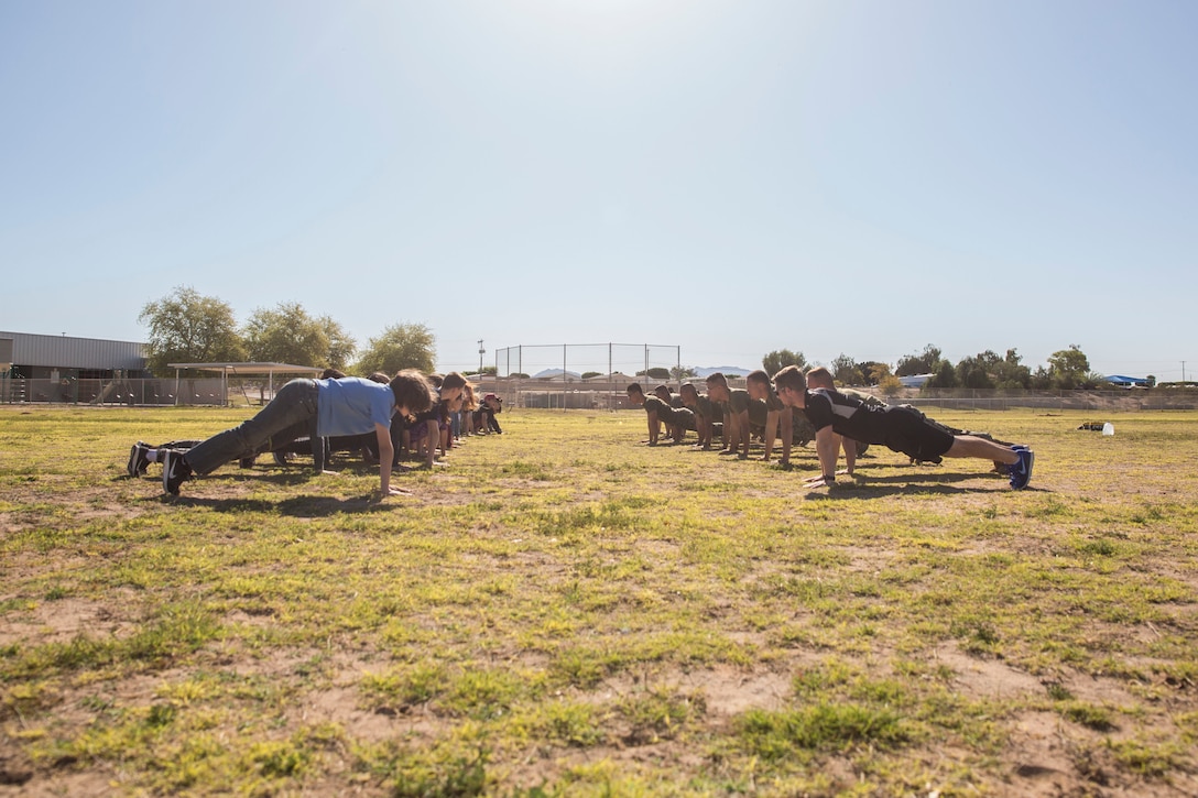 U.S. Marines assigned to Marine Air Control Squadron (MACS) 1 participate in MACS-1's Marine Week at Ron Watson Middle School in Yuma, Ariz., March 29, 2019. The third and last day of Marine Week consisted of students conducting a modified Combat Fitness Test, tasting food from Meal, Ready-to-Eat (MRE), trying on Marine Corps equipment; flak jackets, gas masks, etc., and interacting with the Marines. (U.S. Marine Corps photo by Cpl. Sabrina Candiaflores)