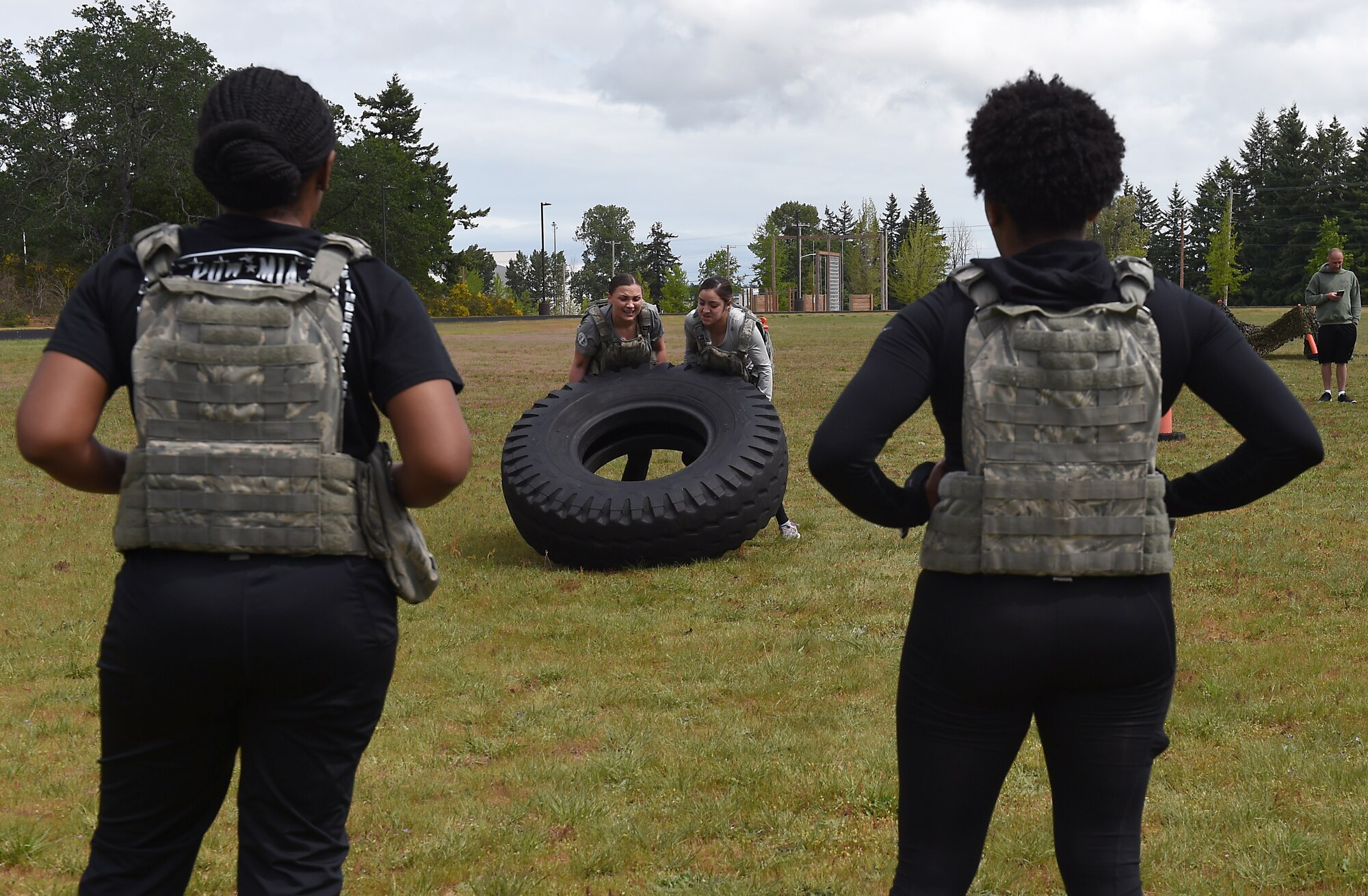 Tech Sgt. Rachel Farella, 627th Force Support Squadron (FSS) non-commissioned officer in charge (center left), and Senior Airman Brittany De La Rosa, 627th FSS evaluations technician (center right), flip a tire towards their teammates Tech Sgt.  LaQuanna Jenkins, 627th FSS non-commissioned officer in charge of career development (left), and Staff Sgt. Tenee Johnson, 627th FSS evaluations technician as part of the Joint Base competition of the McChord Field track May 17, 2019.