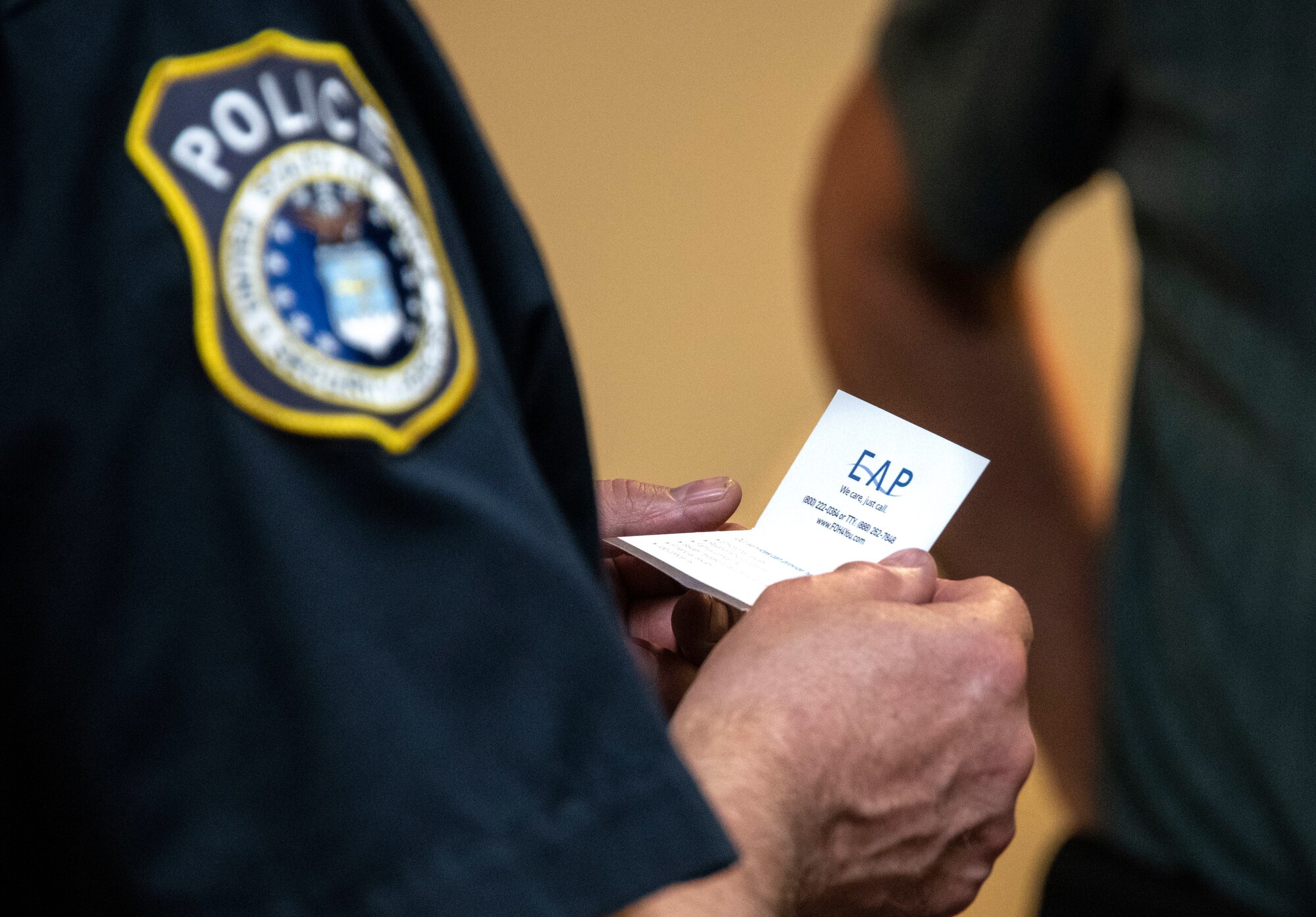 A law enforcement member assigned to the 97th Security Forces Squadron reads a business card for the Air Force’s Employee Assistance Program (AF EAP)