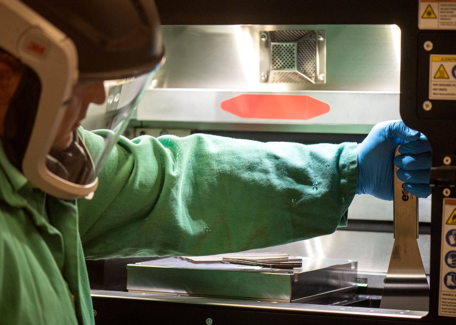 Chuck Self, Naval Surface Warfare Center Panama City Division additive manufacturing laboratory head, prepares the metal 3-dimenstional printer by loading powdered metal.