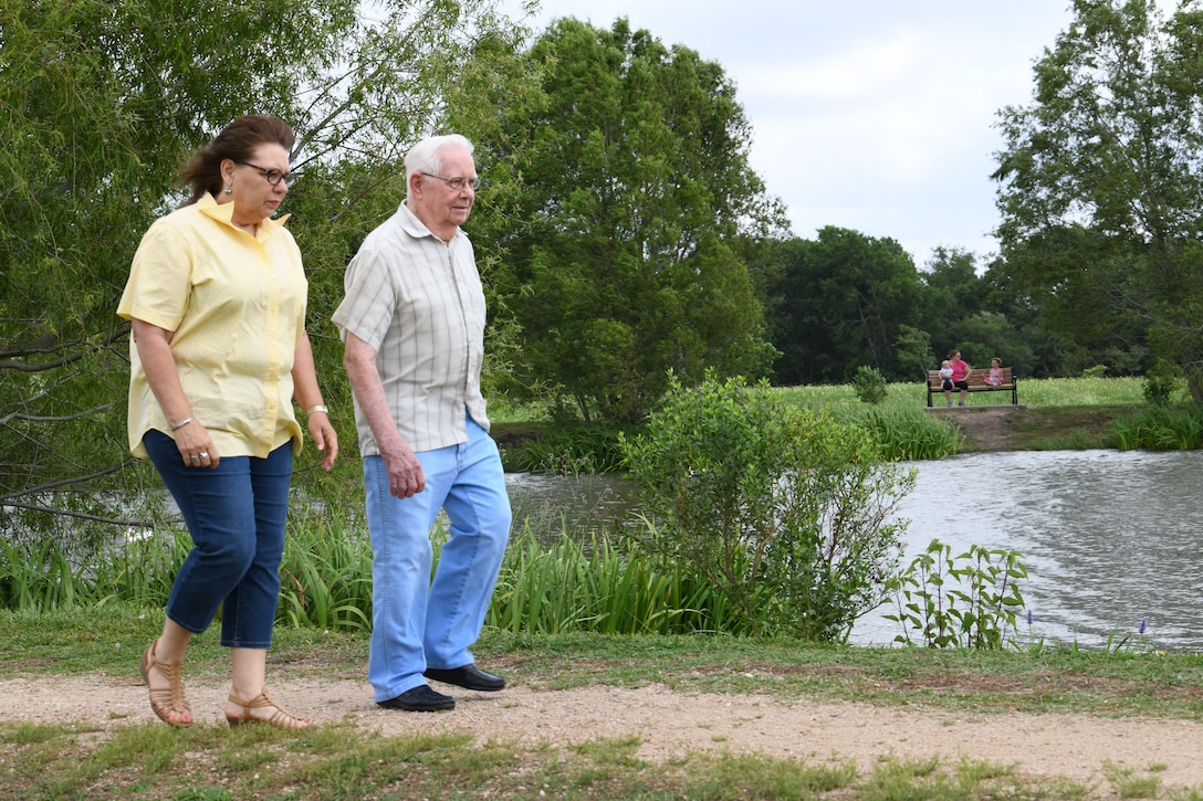 A World War II vet and his daughter take a stroll by a park lake.