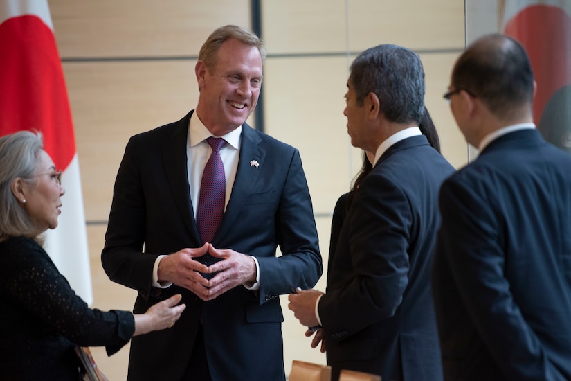 An American official greets three people.