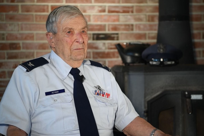 A World War II vet wearing a dress uniform sits by a fireplace.