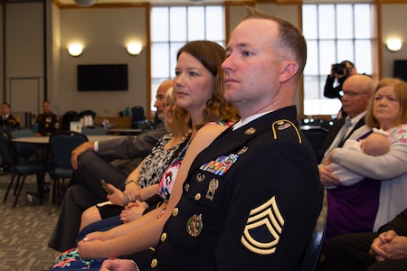 Sgt. 1st Class Greg Waters, his wife and family listen as Maj. Gen. Frank Muth delivers the opening remarks for the ceremony.