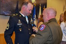Maj. Gen. Frank Muth adjusts Sgt. 1st Class Greg  Waters newly pinned Distinguished Service Cross medal.