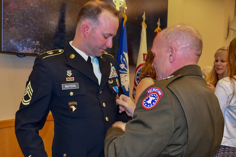 Maj. Gen. Frank Muth adjusts Sgt. 1st Class Greg  Waters newly pinned Distinguished Service Cross medal.