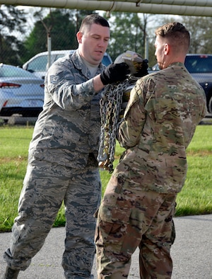 Tech. Sgt. Matthew Foster hands chains to Tech. Sgt. David Richards during a time chain drag competition at the 87th Aerial Port Squadron Port Dawg Challenge May 5, 2019. Both Airmen are load planning specialists with the 87th APS.