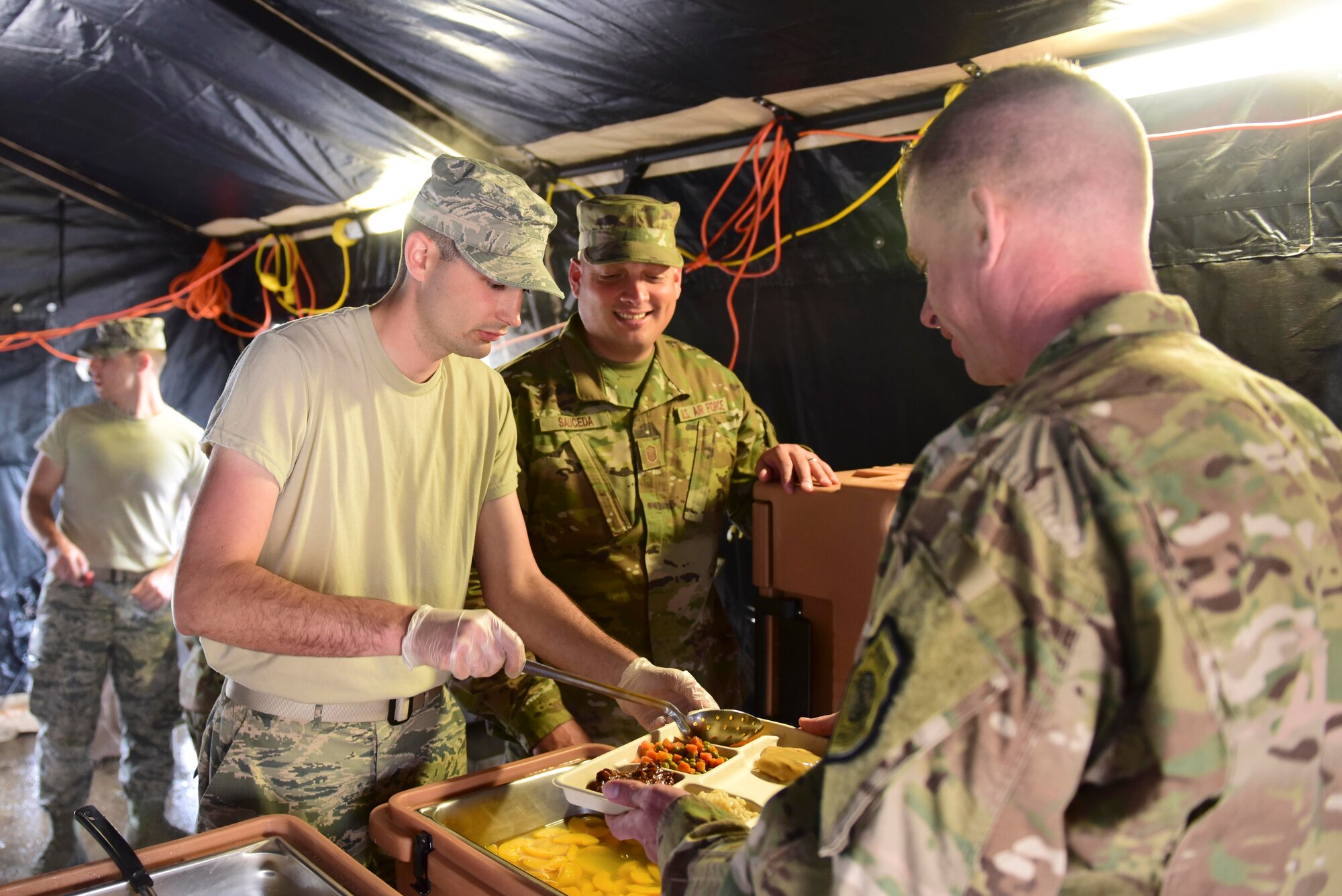 Airman Shane Bradshaw, 31st Force Support Squadron fitness apprentice, serves food from inside a single pallet expeditionary kitchen to Lt. Col. Brian Robertson, 606th Air Control Squadron commander, outside Pula, Croatia, May 28, 2019. FSS Airmen can be pulled from any facility, including fitness centers, to support SPEK operations. (U.S. Air Force photo by Tech. Sgt. Tory Cusimano)