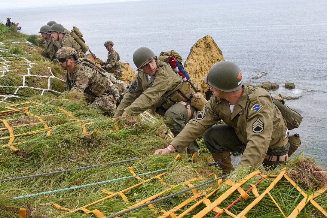 Soldiers climb a cliff using ladder netting