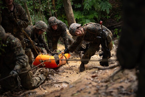 Sailors pull a stretcher up a hill.