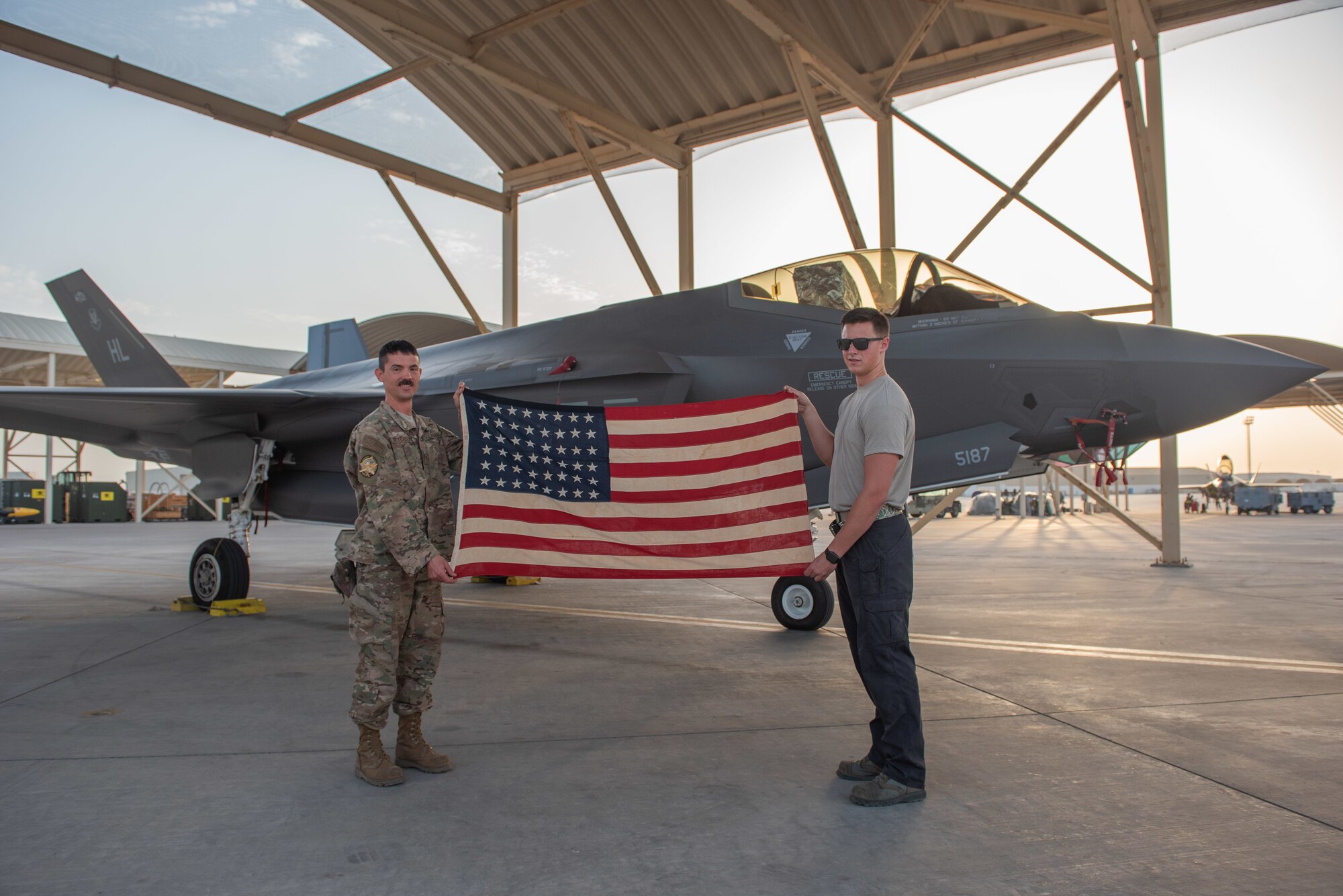 Tech. Sgt. Kenneth Peterson, left, and Senior Airman Quinton Bullock, 380th Expeditionary Aircraft Maintenance Squadron F-35A Lightning II crew chiefs, hold a 48-star flag June 6, 2019, at Al Dhafra Air Base, United Arab Emirates.