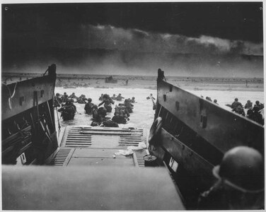 U.S. Soldiers disembark a landing craft under heavy fire off the coast of Normandy, France, June 6, 1944.