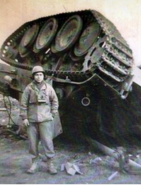 Cpl. Herman Zeitchik, 42nd Field Artillery, 4th Infantry Division, stands beside a destroyed tracked vehicle in Normandy, France, in 1944.