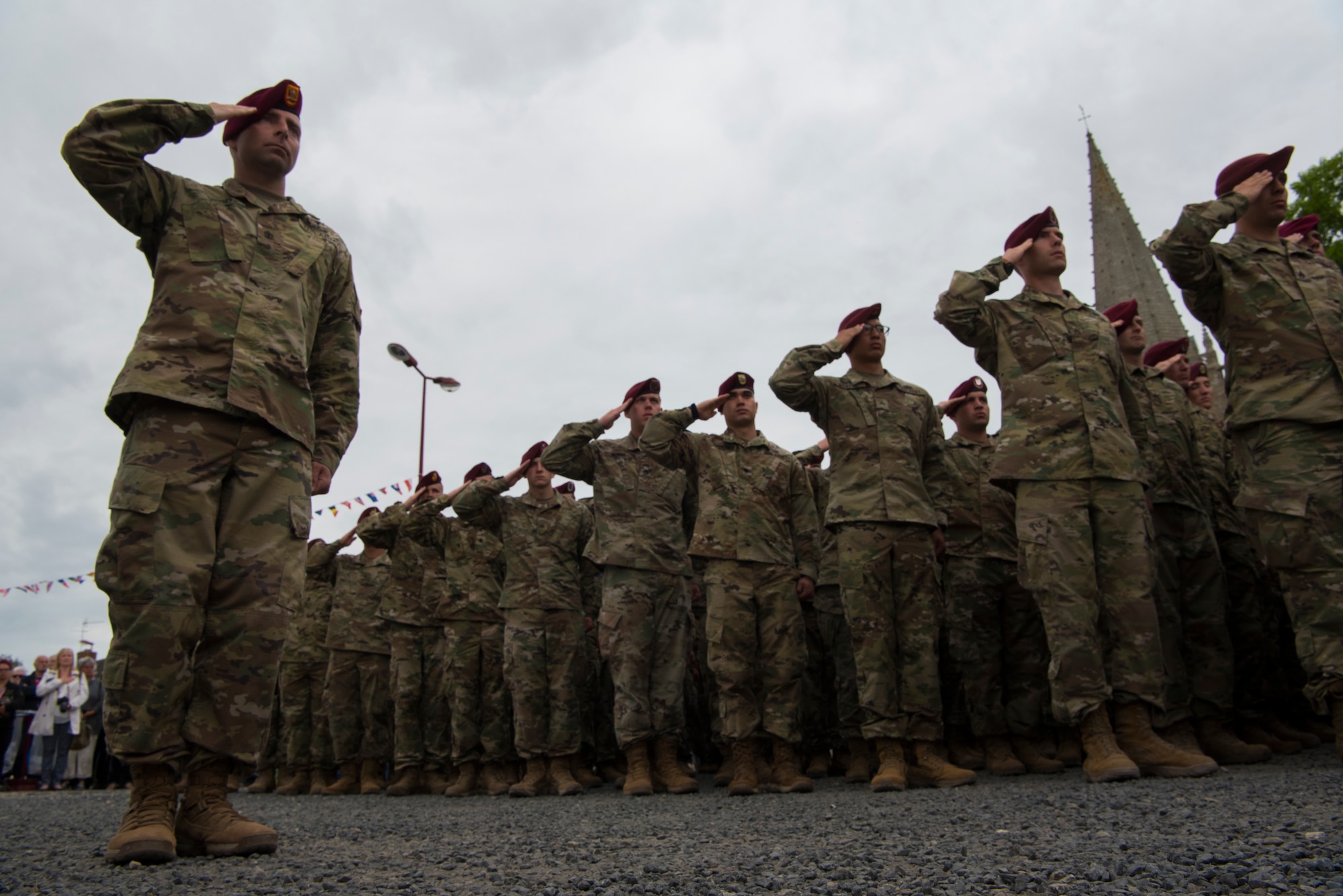 U.S. Army soldiers from the 82nd Airborne Division in Fort Bragg, North Carolina, 173rd Airborne Brigade Combat Team in Vicenza, Italy, and 93rd Infantry Brigade out of Oklahoma and Arkansas salute at the position of attention while the United States, German and French national anthems were played during a ceremony honoring all airborne troops and flight crew that served on D-Day in Picauville, France, June 4, 2019. The soldiers’ presence in the ceremony highlights the strength of the U.S. commitment to European security as they pay respects during the D-Day 75th anniversary commemorations. (U.S. Air Force photo by Senior Airman Kristof J. Rixmann)