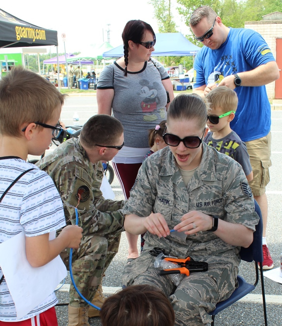 Air Force Technical Sgt. Jennifer Unthank demonstrates basic cable making to a young visitor at the Armed Forces & National Police Celebration. The kids provided the last touch to the cables by crimping the ends.