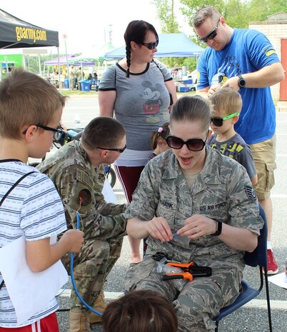 Air Force Technical Sgt. Jennifer Unthank demonstrates basic cable making to a young visitor at the Armed Forces & National Police Celebration. The kids provided the last touch to the cables by crimping the ends.